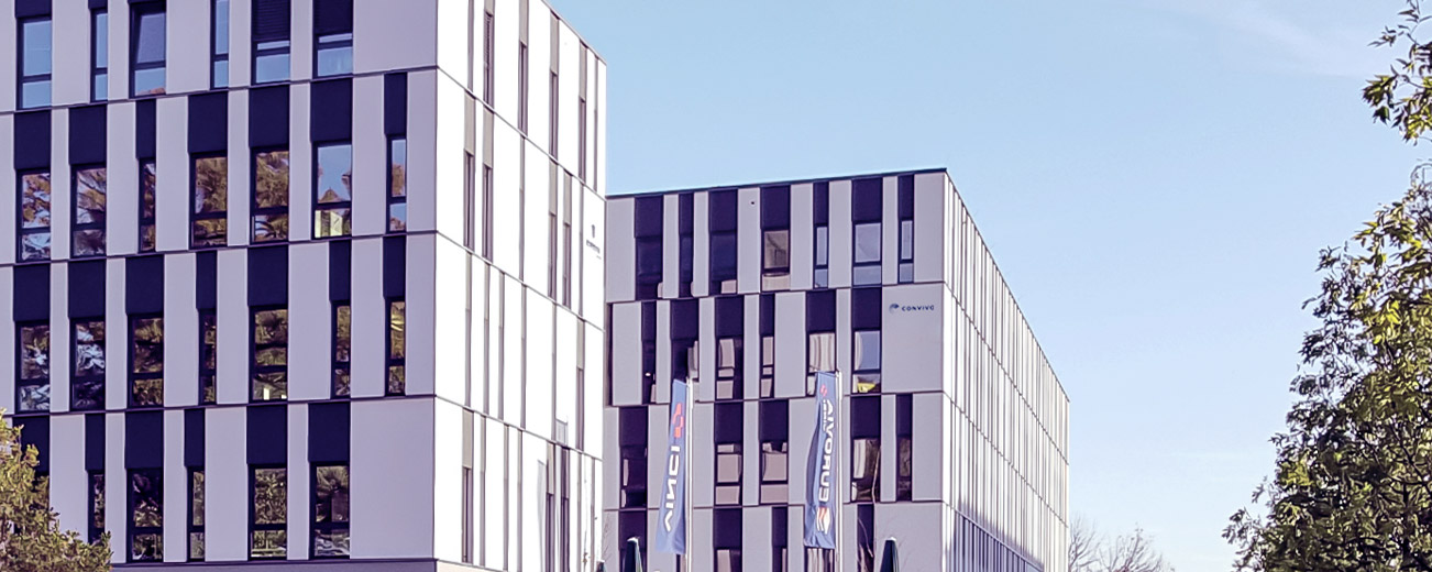 Gebäudekomplex der convivo GmbH in Adlershof mit convivo Logo auf der Fassade, Außenansicht im Sommer